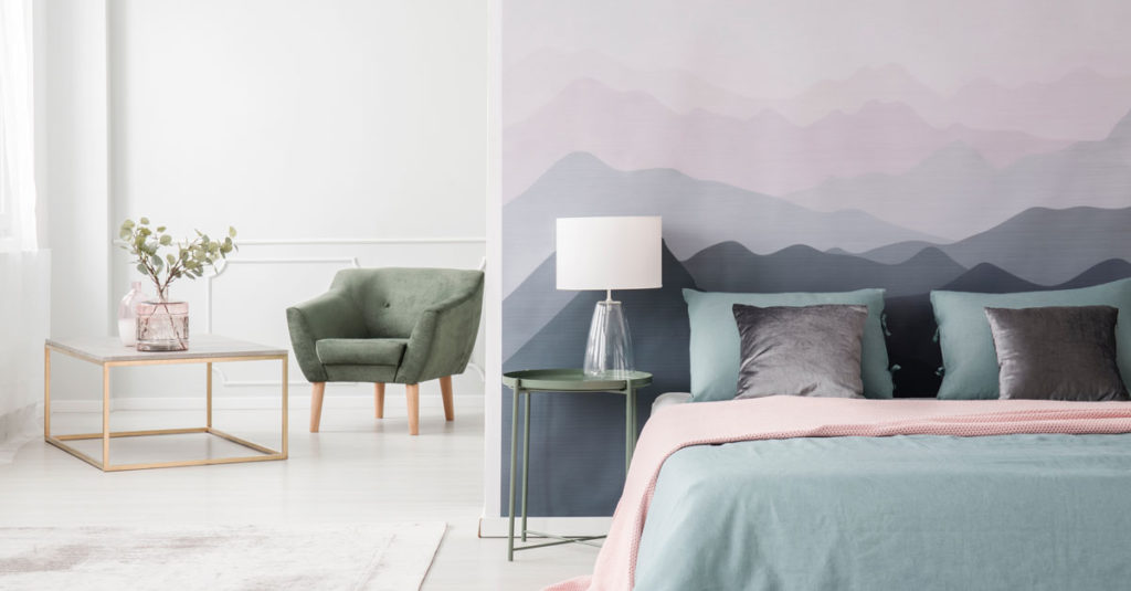 a bedroom with a blue bed and wallpaper with a mountain design