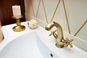 a sink with a brass faucet and a brass candle 