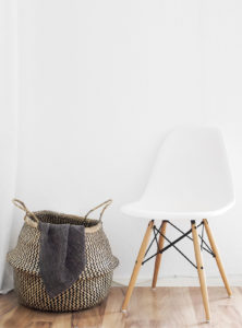 a large woven basket next to a modern white chair